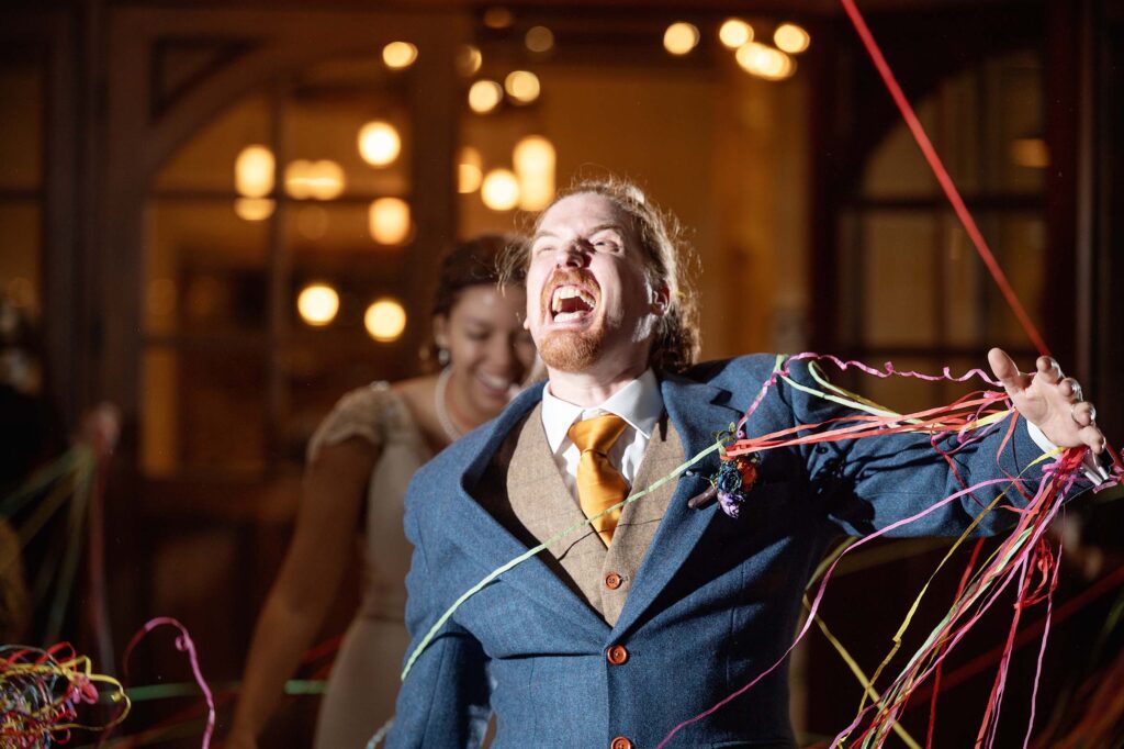 Groom pushing colorful streamers away during grand exit wedding photos